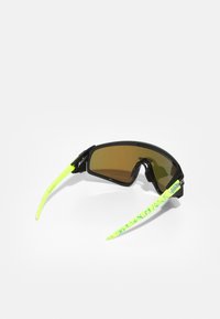 Óculos de sol desportivos com uma armação preta, lentes castanhas e braços amarelos-neon com um padrão texturizado. Design leve e aerodinâmico.