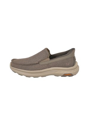 Zapato casual de tipo slip-on con parte superior de tejido de punto beige, suela acolchada beige y logotipo de Goodyear en la suela del talón.