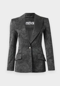 Black blazer with jacquard pattern, single button closure, peak lapels, two front pockets, and branding inside. Smooth texture.