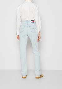 Ljust blå denimjeans med rak benstil, som har två bakfickor och en Tommy Hilfiger-logotagg vid midjan.