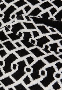 Zwart-wit gemusterde stof met geometrische vormen, met een zachte textuur en een gebreide afwerking, wat zorgt voor een modern ontwerp.