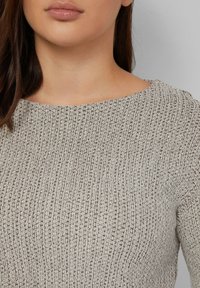 Gebreid top met een geribde textuur in beige met bruine spikkels, ronde halslijn en korte mouwen, met nadruk op een aansluitend ontwerp.