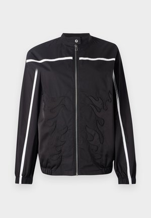 Črna jakna z visokim ovratnikom, zadrgo, belimi stranskimi črtami in vezenjem plamena spredaj. Narejena iz lahkega materiala.