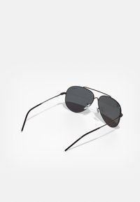 Černé kovové aviator brýle s tmavými čočkami, mají tenký rám a štíhlé nožičky, navrženy v klasickém tvaru.