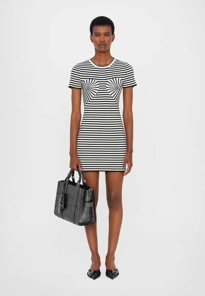 Gestreepte bodycon jurk in zwart en wit, met een gestructureerd strikontwerp. Gecombineerd met een gestructureerde zwarte handtas en zwarte puntige schoenen.