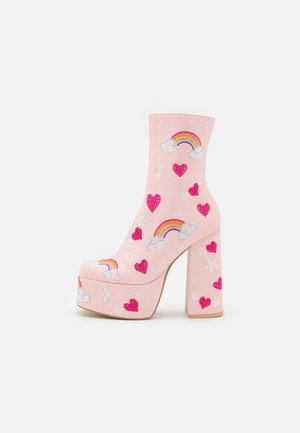 Pink platform-ankelstøvle med blokhæl, dekoreret med broderede regnbuer, røde hjerter, hvide stjerner og skyer.
