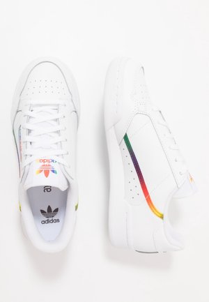 Baskets blanches Adidas avec des bandes aux couleurs de l’arc-en-ciel sur les côtés et logo de la marque sur la languette, vues de dessus et de côté.