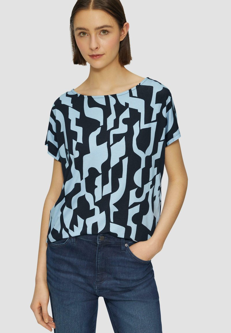 Blauw en zwart gestreepte top met korte mouwen en een losse pasvorm, met abstracte vormen en een brede boot halslijn. Gecombineerd met donkere jeans.