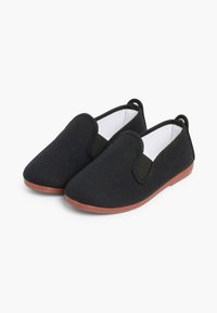 Zwarte canvas instap schoenen met elastische zijkanten, textielstof en een bruine rubberen zool. Eenvoudig ontwerp, ronde neus, minimale details.