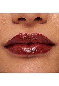 Tiefrote, glänzende Lippen mit einer definierten Form und glatter Textur, die einen subtilen Kontrast zur umgebenden Haut bilden.