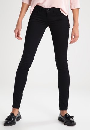 Zwarte skinny jeans van rekbaar materiaal, met een klassieke vijf-pocketdesign en subtiele stiksels. Gecombineerd met zwarte instapper.
