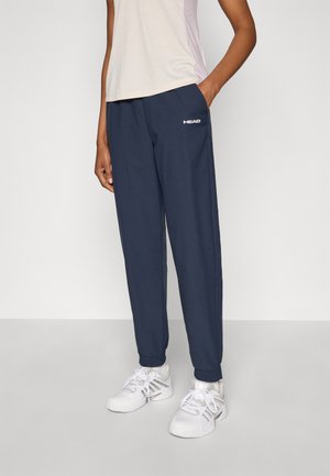 Námornícky modré joggové nohavice s elastickými manžetami, vybavené bočnými vreckami a potlačeným bielym logom. Nosené s svetlým, krátkym rukávom.