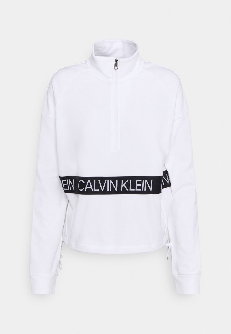 Pull-over blanc à manches longues avec une demi-fermeture éclair et une bande noire à la taille affichant le logo Calvin Klein en lettres blanches.