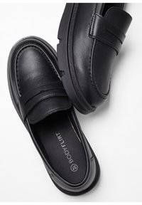 Mocassins en cuir noir avec une texture lisse, des détails cousus et un bout arrondi, dotés d'une semelle robuste légèrement surélevée.