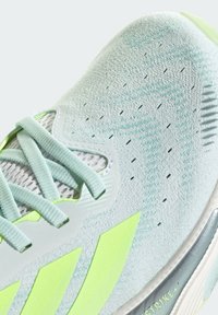 Lichtblauwe sportschoen met een bovenwerk van mesh, groene accenten en een textuur oppervlak. Voorzien van platte veters en opvallende zijlogostrepen.
