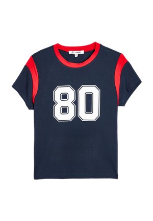 Marineblauwe t-shirt met rode accenten op de mouwen, een ronde hals en een groot wit nummer "80" gedrukt op de voorkant. Zachte stofstructuur.