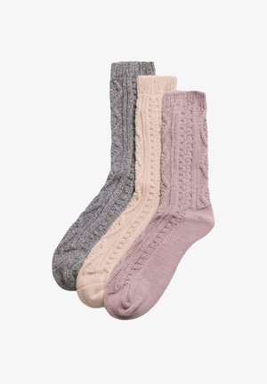 Conjunto de tres calcetas de punto texturizado en gris, rosa claro y malva, con patrones de trenzas y puños acanalados.