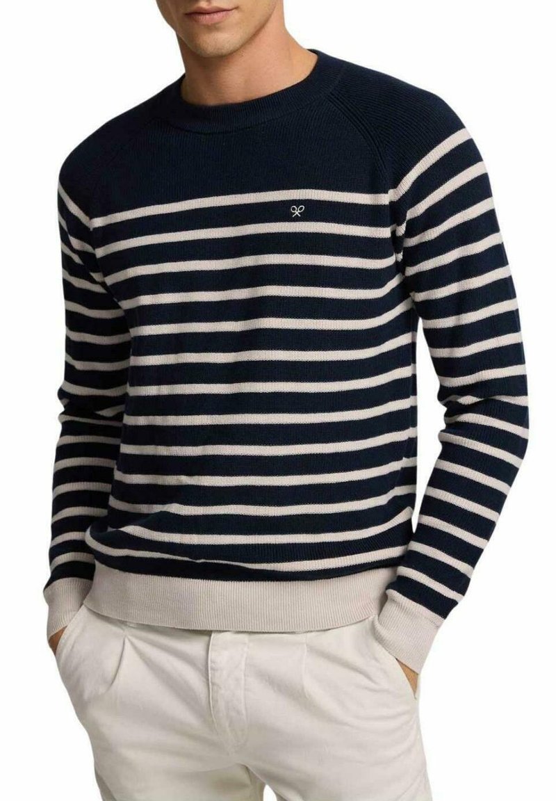 Suéter de punto a rayas azul marino y crema con cuello redondo, puños y dobladillo acanalados. Presenta un pequeño logo en el pecho.