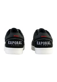 Zapatillas negras con una parte superior de tela texturizada, logo blanco en el talón y suela de goma blanca. Detalle rojo en la parte trasera. Diseño informal.