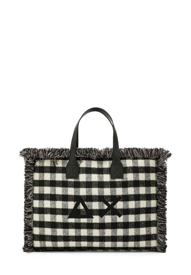 Borsa tote a scacchi bianco e nero con bordi sfilacciati, dotata di manici in pelle nera e un logo al centro. Texture e design distintivi.