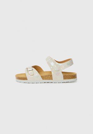 Sandal com um cabedal brilhante de cor clara, apresentando um padrão floral. Palmilha de cortiça e tira ajustável com detalhes em prata. Sola branca.