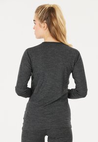 Langärmliges, dunkelgraues Oberteil aus weichem, dehnbarem Stoff. Es hat einen runden Ausschnitt und eine figurbetonte Silhouette mit einer glatten Textur.