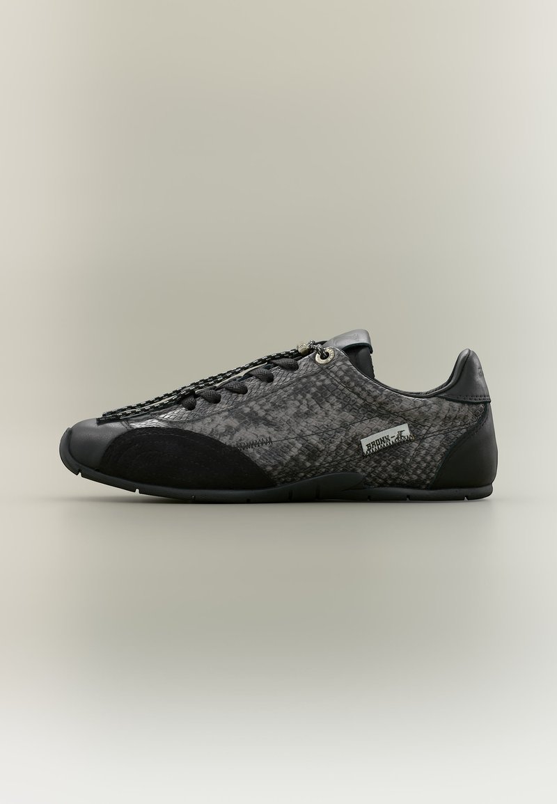 Baskets noires et grises à profil bas avec motif texturé, bout et talon noirs, lacets noirs et petite étiquette de marque sur le côté.