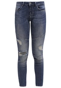 Jeans ajustados en denim oscuro con secciones descoloridas, rasgones en las rodillas y diseño tradicional de cinco bolsillos. Presenta un cierre con botón de metal.
