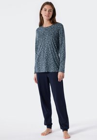 Long-sleeve top in teal with a black abstract pattern, paired with navy blue jogger pants, both made from soft, smooth fabric.
