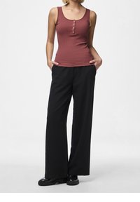 Top con scollo a V in maglia di cotone color bordeaux con chiusura a bottoni, abbinato a pantaloni larghi neri con una texture liscia e una silhouette aderente.