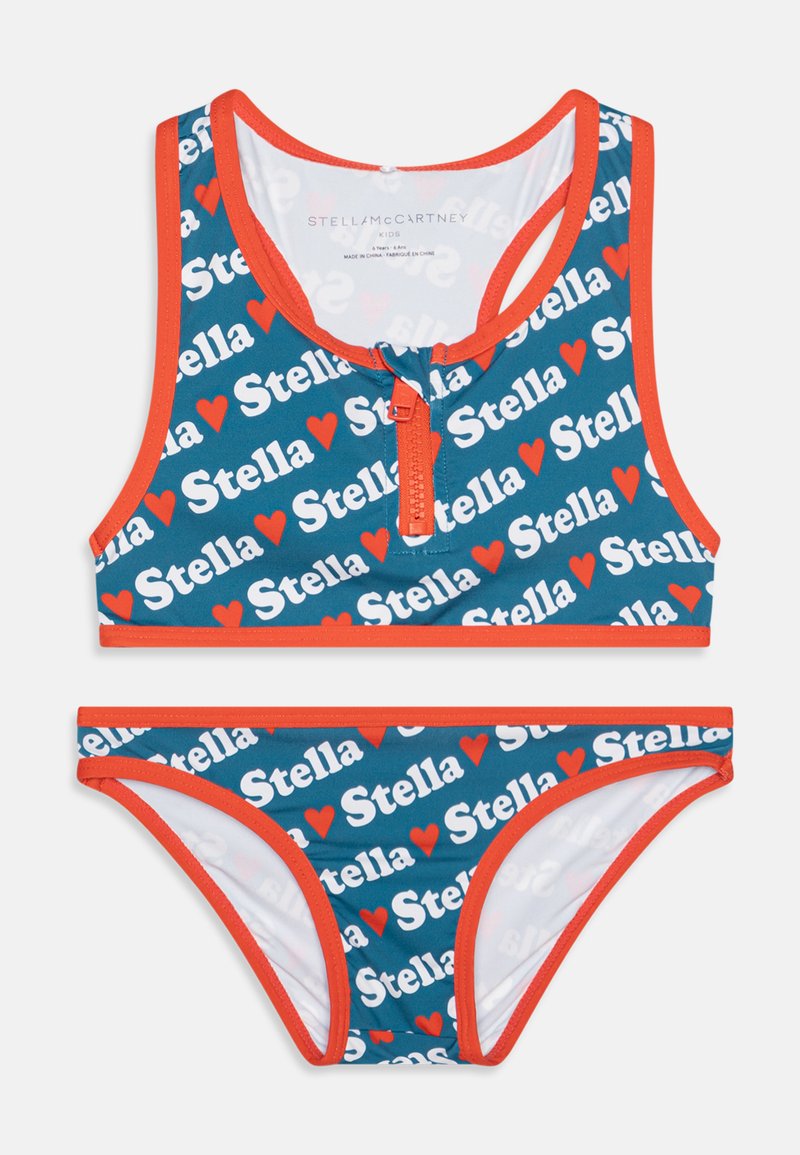 O conjunto de banho em duas peças para crianças apresenta uma base azul com o texto repetido "Stella" em branco e corações vermelhos, acentuado por um vivo vermelho e fecho com zíper.
