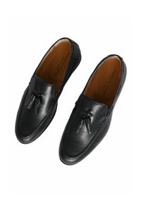 Mocassini in pelle nera con una texture liscia, con dettagli a nappina sulla parte anteriore e suola cucita. Made in Italy.