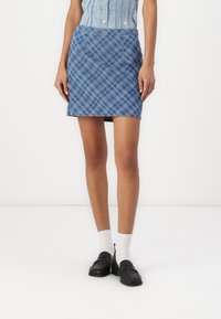 Denim minikjol med blå rutmönster och vita detaljer, två framfickor och en figursydd silhuett.