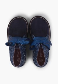 Zapatos de ante azul marino con acentos brillantes en azul y un lazo de cinta satinado. Punta redondeada, plantilla acolchada y costura visible alrededor de la suela.