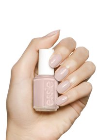Flacon de vernis à ongles avec un capuchon blanc dans une teinte rose clair. Peint à la main avec un vernis assorti de couleur rose clair montrant une texture lisse et brillante.