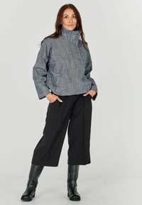 Hall värvi tekstureeritud kootud särk kõrge kraega, koos mustade laia säärega pükstega ja põlvini ulatuvate mustade saapastega. Lihtne disain, lõdva istuvusega.