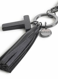 Sleutelhanger met een zwart, gespikkeld plastic letter 'T' en een zwarte leren franje. Inclusief een ronde metalen ring en een bedel gegraveerd met "MIRIADA."
