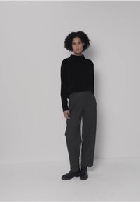Pull à col roulé noir, pantalon gris à jambes larges, bottes noires ; textures lisses, coupe décontractée, design minimaliste, palette de couleurs neutres.