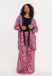 Loungeset met luipaardprint in roze en paarse tinten, bestaande uit een lange cardigan met marineblauwe bies en bijpassende wijde broek. Gestructureerde, zachte stof.