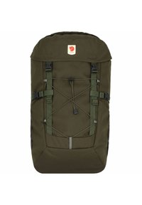 Dark green backpack made of durable fabric, featuring a top flap, adjustable straps, and bungee cord for extra storage. Logo patch on front.