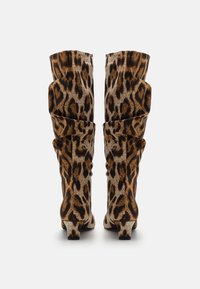 Bottes genouillère imprimé léopard avec un design froissé, featuring un tissu texturé et un petit talon bloc. Les couleurs dominantes sont le marron et le beige.
