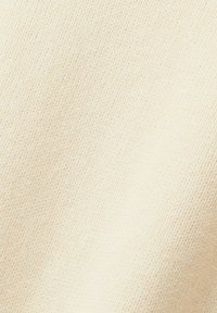 Tissu tricoté couleur crème avec une texture fine, tissée serrée et un subtil motif côtelé diagonal.