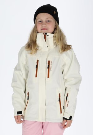 Hvid vandtæt jakke med brune lynlåsdetaljer, høj krave og flere lommer, båret over lyserøde bukser. Modellen har en sort strikket hue på.