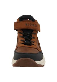 Baskets montantes en daim marron et synthétique noir avec lacets, bande ajustable et semelle en caoutchouc texturé. Nom de la marque "MUSTANG" visible.