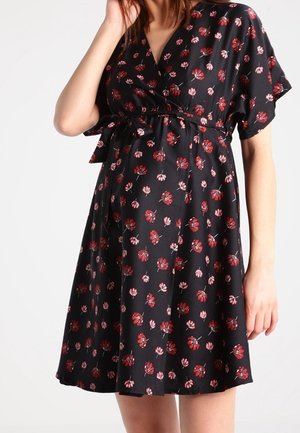 Czarna sukienka opaska z krótkimi rękawami, z kwiatowym wzorem w czerwieni i różu. Miękki materiał z detalem w postaci przewiązania w talii.