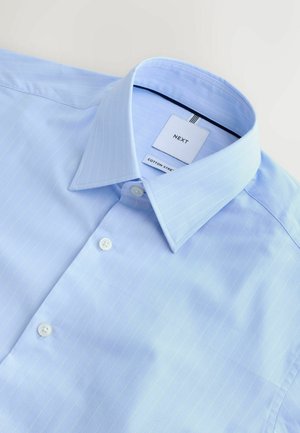 Svetlomodrá bavlnená košeľa s jemnými zvislými pásikmi, špicatým golierom a bielymi gombíkmi. Na štítku je nápis „NEXT COTTON STREET.“