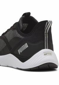 Musta ja harmaa urheilukenkä, jossa on teksturoitu päällinen, valkoinen pohja ja "PUMA"-brändäys sivussa. Sisältää pehmeän kantapään ja korostuksia.