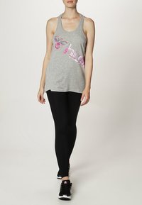 Grijze tanktop met een roze grafisch ontwerp, gecombineerd met zwarte leggings en zwarte sportschoenen. Glad materiaal, sportieve pasvorm en mouwloos ontwerp.