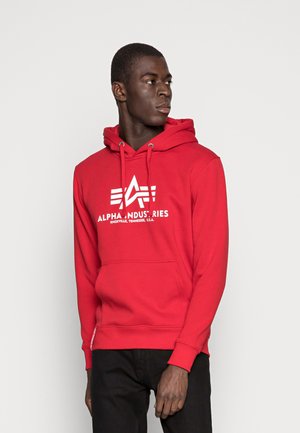 Sudadera roja de algodón con un bolsillo frontal, que presenta un logotipo blanco con estrella y acentos de texto. Incluye cordones en la capucha.