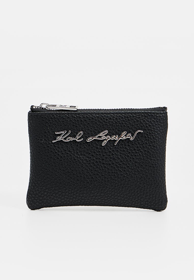 Billetera de cuero texturizado negro con cierre de cremallera y un logo plateado en relieve en la parte frontal. Forma rectangular compacta.